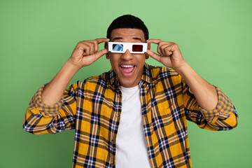 Photo of overjoyed cheerful person open mouth hands touch 3d glasses watch movie isolated on green...