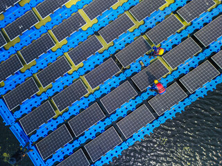 Top aerial of Male workers repair Floating solar panels on water lake. Engineers construct on site Floating solar panels. clean energy for future living. Industrial Renewable energy of green power.