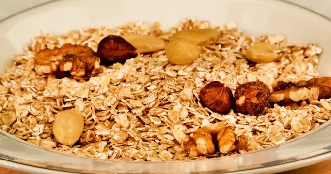 Spelled flakes on a plate with breakfast cereals and nuts. Spelled is by far the richest in vitamins and protein.