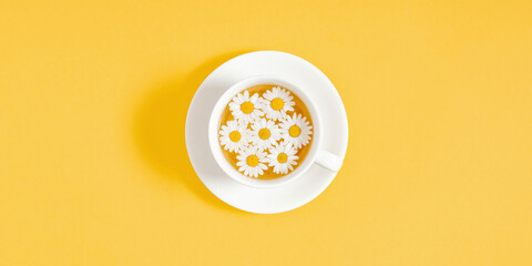 White chamomiles, cup of tea on yellow background. Herbal tea of chamomile flower. Chamomile tea...