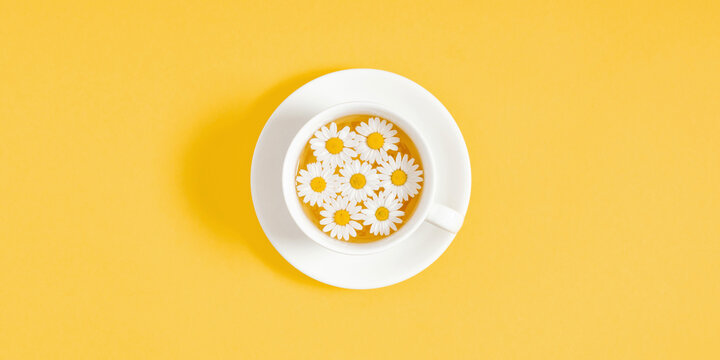 White chamomiles, cup of tea on yellow background. Herbal tea of chamomile flower. Chamomile tea concept. Flat lay, top view, copy space - Powered by Adobe