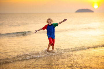 Child playing on ocean beach. Kid at sunset sea.