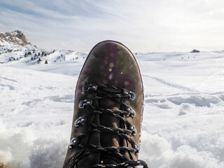 A hiker's boot in the snow indolomites snow panorama wooden hut val badia armentarola hill