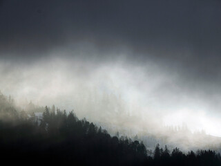 Foggy sunrise on Cross Mountain peak Monte croce sun rays passing through clouds in winter...