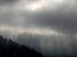 Foggy sunrise on Cross Mountain peak Monte croce sun rays passing through clouds in winter...