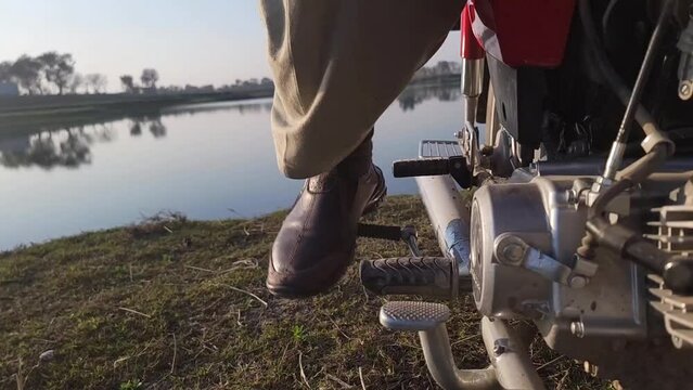 A man is kick-starting a motorcycle. Beautiful slow motion video۔ Motorcycle kick to start up in slow motion 480fps.
