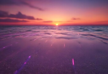 A sunset on a beach with purple and pink hues in the sky reflecting on the wet sand and shallow sea water