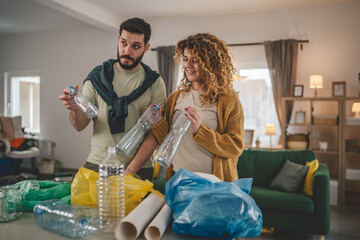 husband and wife recycle at home sorting waste plastic paper and glass