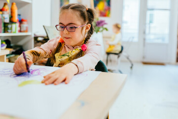 Little girl who have down syndrome in kindergarten class doing art project.