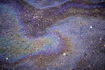 Textured stain of fuel or oil on wet asphalt on a rainy day. The concept of environmental pollution