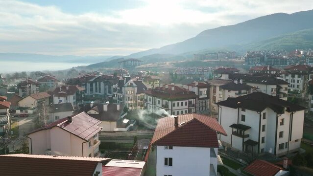 Bansko drone video, rising high above buildings and beautiful hilly landscapes at the foot of Pirin Mountains, snowless winter shot.