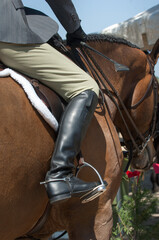 hunter jumper apparel beige breeches tall black riding boots grey hunter jacket close up of horse riding dress horse show attire rider carrying crop horse in english tack rider in english show attire 