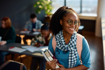 Happy black female university student in classroom looking away.