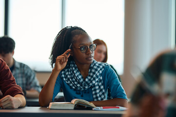 Pensive black female student learning at college classroom and looking away.