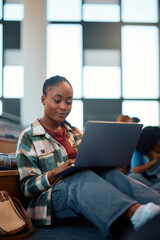 Smiling black female student using laptop while learning at campus.