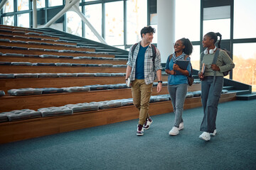 Happy students communicating while leaving amphitheater after lecture at university.