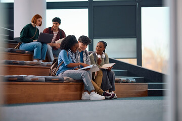 Multiracial group of university friends studying in lecture hall at campus.