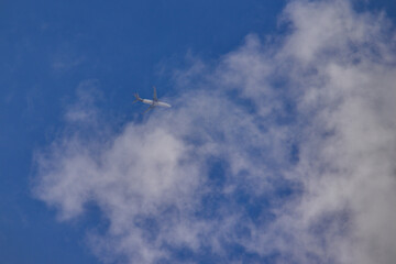 jet plane flying at high altitude among thin white clouds in a blue sky.