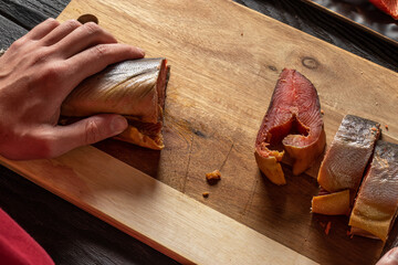 Close-up of hands cutting pink salmon into large pieces. Smoked humpback salmon. Oncorhynchus...
