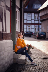 Reflective Young Woman Sitting on Steps in Quaint European Street