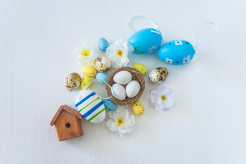 Happy easter holidays concept; Easter eggs, birdnest with eggs and flowers on a white background; top view