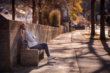 Young Woman Basking in the Warmth of the Sun on a City Bench