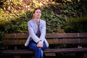 Fototapeta premium Relaxed Young Woman Stretching on a Park Bench Amidst Nature