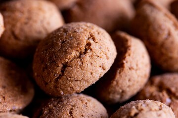 A single pepernoot, a delicious dutch treat lying on a pile of others of its kind. These peppernuts, gingerbread or kruidnoten are a traditional snack during the holidays and sinterklaas.