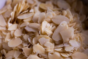 A food closeup portrait of a lot of tasty almond flakes in it used by a baker to create tasty cookies or pastries. The chopped up crunchy cooking and baking ingredient is ready to be used.