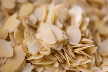 A delicious closeup portrait of a pile of almond flakes in it used by a baker to create tasty cookies or pastries. The chopped up crunchy cooking and baking ingredient is ready to be used.