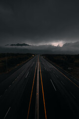 Moody dark picture of highway after rain with clouds and mountains 