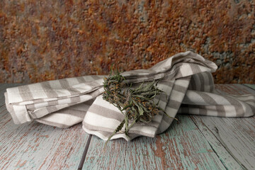White dish towel on old table with dry marijuana blossom and rusty metal wall