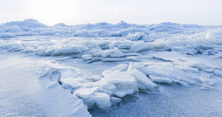 Ice hummocks covered with snow. Panoramic landscape photo with coast of frozen Baltic Sea on cold winter day