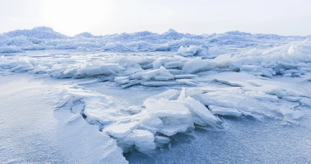 Fotobehang Blauwe hemel Ice hummocks covered with snow. Panoramic landscape photo with coast of frozen Baltic Sea on cold winter day  © evannovostro