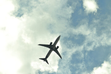 semi silhouette of jet plane flying under a blue sky covered by white clouds.