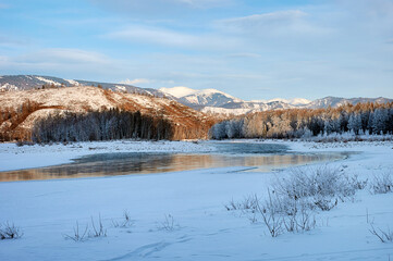Snowcovered mountain landscape with a frozen river and cloudy sky.