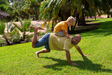 Father and son are playing on the lawn. son tickles father's leg. father and son having fun on...