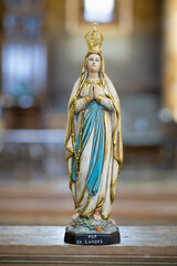 Statue of Our Lady of Lourdes in blurred religious church background