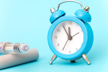 insuline pen and blue clock on blue background