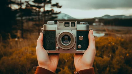 Photo sur Plexiglas Mont Cradle Hands cradle a vintage camera against a mountainous backdrop, capturing not just a scene but the essence of nostalgic photography and timeless adventure.