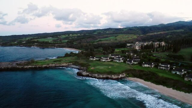 Aerial Descending Forward Shot Of Sea Near Houses And Mountain On Coastline Against Sky At Sunset - Maui , Hawaii