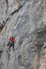 Man in red t-shirt scalded on gray wall, playing sports, reaching limit