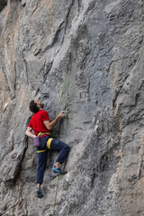 Man in red t-shirt scalded on gray wall, playing sports, reaching limit