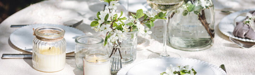 Romantic elegant luxury wedding table decor with white fresh spring blooming cherry apple tree flowers. Glass, candles, floral decoration for special marriage holiday event. Zero waste, banner