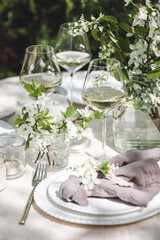 Romantic elegant luxury wedding table decor with white fresh spring blooming cherry apple tree flowers. Glass, candles, floral decoration for special marriage holiday event. No plastic zero waste