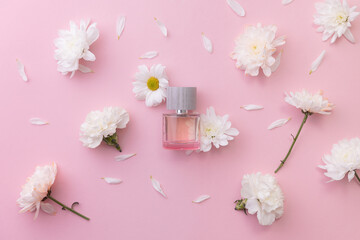 Perfume bottle spring aroma amidst white flowers on pink surface, Flat lay