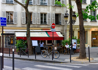 Parisian street with tables with tables of cafe in Paris, France. Architecture and landmark of Paris. Cozy Paris cityscape