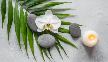 Obraz na płótnie Canvas spa stones palm leaves flower white orchid candle and zen like grey stones on white background flat lay top view
