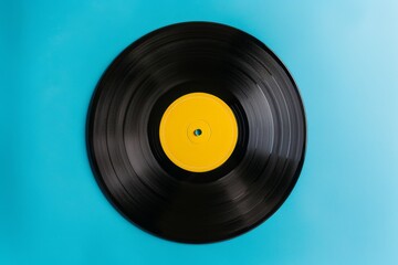 Front view closeup of a black vintage vinyl record isolated on a cyan background with a yellow label