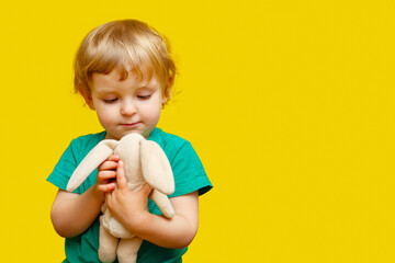 Toddler Embracing Stuffed Animal Against Yellow Background